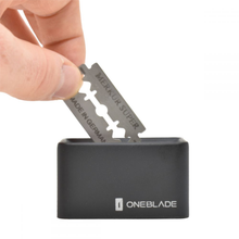 Load image into Gallery viewer, OneBlade black used razor blade bank for used safety razor blades, sustainable shaving. Hand putting used razor into the bank.
