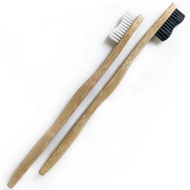 2 x bamboo toothbrushes lying on their side. one with black bristles and one with white bristles 