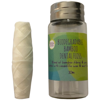 30 meters of biodegradable bamboo dental floss in a glass jar with dental floss out of the jar next to it.